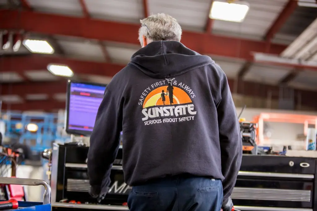 Person standing at computer with their back facing you wearing a hoodie that references safety
